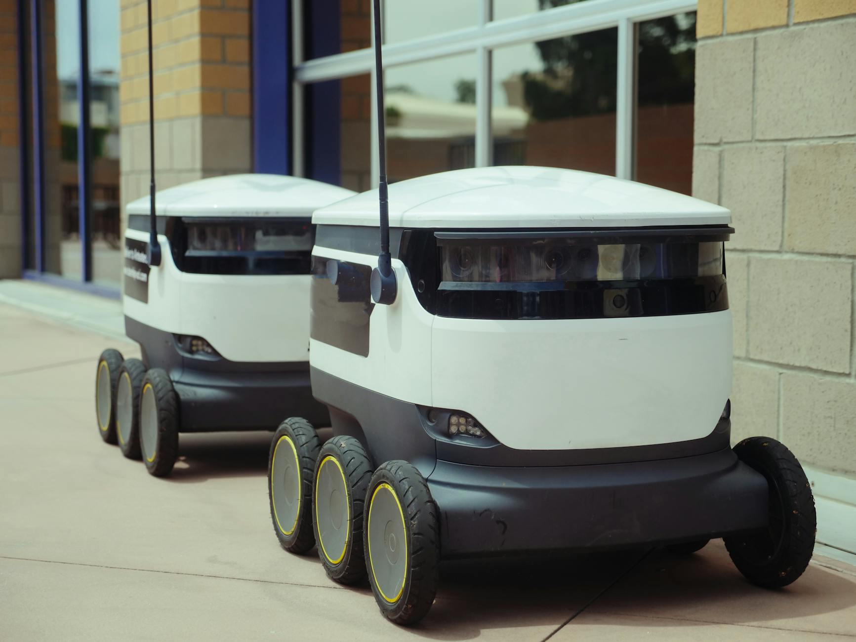 Dwa autonomiczne roboty przed nowoczesnym budynkiem biurowym
